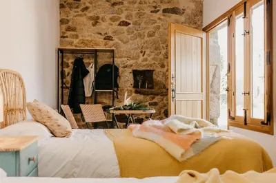 a bedroom with a bed and a stone wall at Casa do Cuco - Rural house in Friol