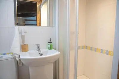 a white bathroom with a sink and a shower at Casa do Cuco - Rural house in Friol