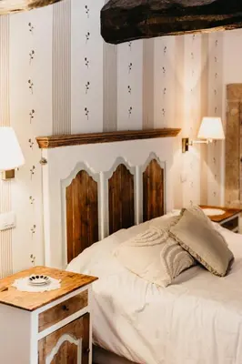a bedroom with a bed with a wooden headboard and a table at Casa do Cuco - Rural house in Friol