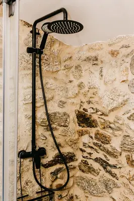 a shower in a bathroom with a stone wall at Casa do Cuco - Rural house in Friol
