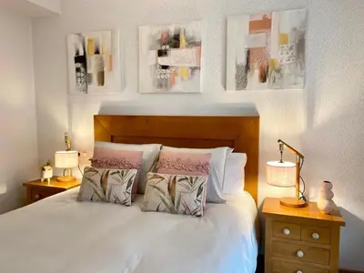 a bedroom with a white bed with two lamps and pictures on the wall at Andainas F in Milladoiro