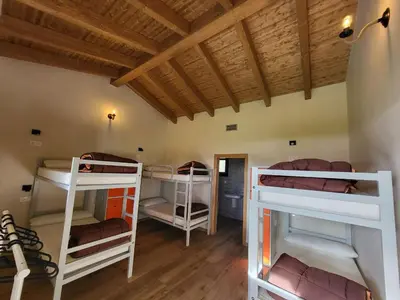a room with three bunk beds and a wooden ceiling at Albergue Los Hospitales in Colinas de Arriba