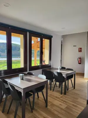 two tables and chairs in a room with windows at Albergue Los Hospitales in Colinas de Arriba