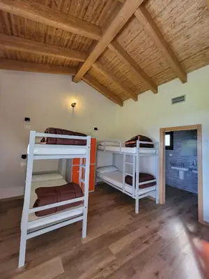 two bunk beds in a room with a wooden ceiling at Albergue Los Hospitales in Colinas de Arriba