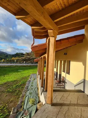 a patio with a wooden roof with a table and chairs at Albergue Los Hospitales in Colinas de Arriba