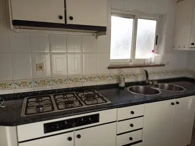 a kitchen with a white table and two windows at Bajo Loft con cocina y baño separados in Cillero