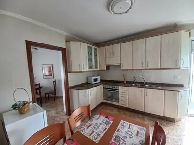 a kitchen with white cabinets and a table and chairs at Piso Villa Aurora in Carballino