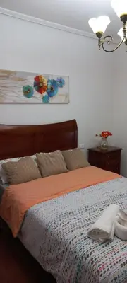 a bedroom with a bed with an orange comforter at Piso Villa Aurora in Carballino