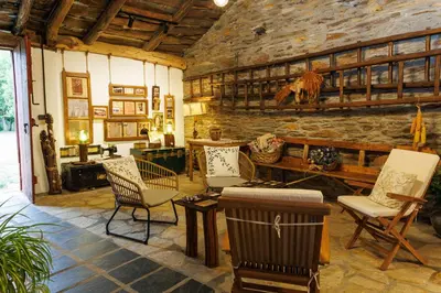 a living room with chairs and a stone wall at Agradable casa de aldea en un entorno natural in Layosa