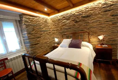 a bedroom with a bed in a stone wall at Agradable casa de aldea en un entorno natural in Layosa
