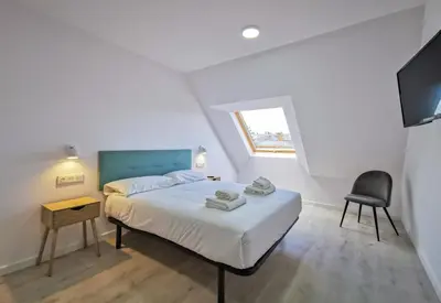 a bedroom with a bed with a chair and a television at Playa de Foz Suites & Spa by gaiarooms in Foz