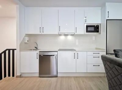 a kitchen with white cabinets and a sink and a dishwasher at Playa de Foz Suites & Spa by gaiarooms in Foz