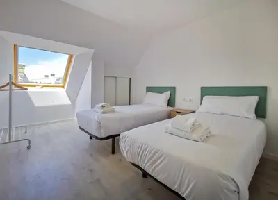 two beds in a room with a window at Playa de Foz Suites & Spa by gaiarooms in Foz