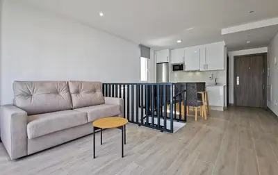 a living room with a couch and a table and a kitchen at Playa de Foz Suites & Spa by gaiarooms in Foz