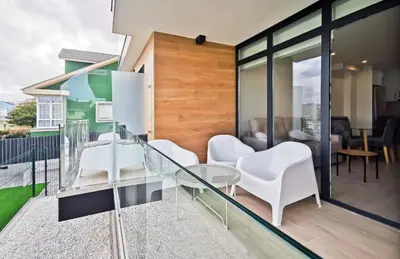 a balcony with white chairs and a glass table at Playa de Foz Suites & Spa by gaiarooms in Foz