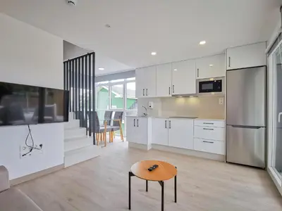 a kitchen with white cabinets and a wooden table at Playa de Foz Suites & Spa by gaiarooms in Foz