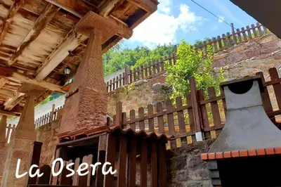 a wooden fence in front of a building with a bell at zentralclub La Osera visionando la naturaleza in Santiago del Hermo