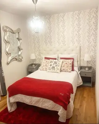 a bedroom with a bed with a red blanket and a mirror at Lula Apartamento in Betanzos