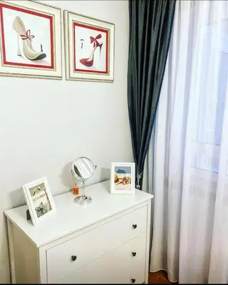 a white dresser with two pictures and a mirror on it at Lula Apartamento in Betanzos