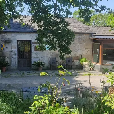 a stone house with a patio and a door at WITERICUS hospedaxe in Guitiriz