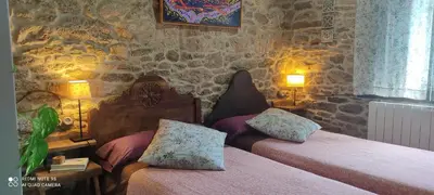 a bedroom with two beds and a stone wall at WITERICUS hospedaxe in Guitiriz