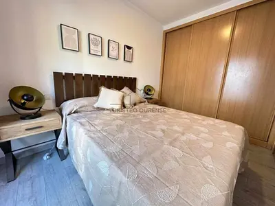 a bedroom with a large bed and a wooden cabinet at A morada das Camelias in Ourense