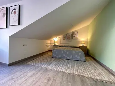 a attic bedroom with a bed and a rug at A morada das Camelias in Ourense