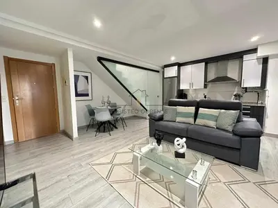 a living room with a black couch and a table at A morada das Camelias in Ourense