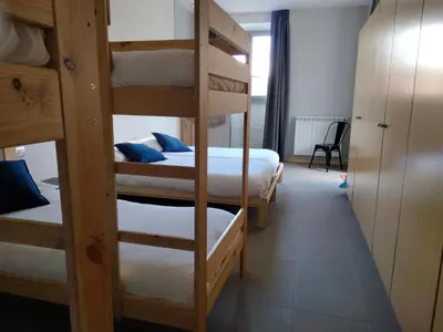 a room with three bunk beds with white sheets and blue pillows at Albergue de Cerceda in Cerceda