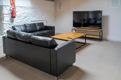 a living room with a black leather couch and a table at Albergue de Cerceda in Cerceda