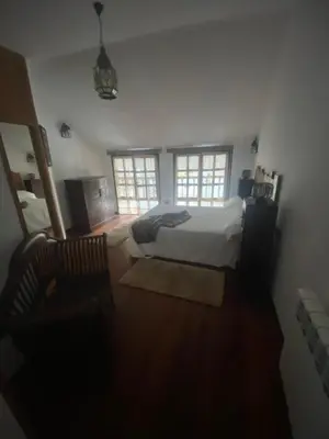 a bedroom with a bed and two windows at La Casina de Somiedo in Pola de Somiedo