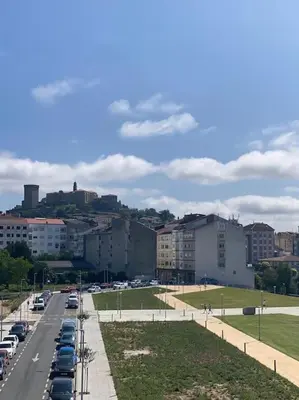 a city street with cars parked in a parking lot at O Lar de Jose in Monforte de Lemos