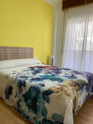 a bedroom with a bed with a blue and white blanket at Coqueto alojamiento cercano a las termas B in Ourense