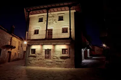 an old building with lights on it at night at Hotel Las Treixas in Puebla de Sanabria