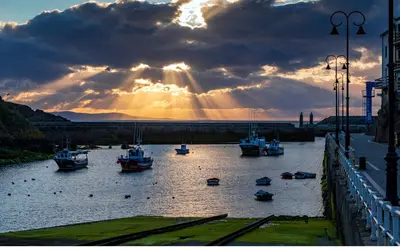 a group of boats in a river with the sun shining at Hacienda El Esteiro - Villas vacacionales in Tapia de Casariego