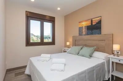 a bedroom with a large white bed and two windows at Hacienda El Esteiro - Villas vacacionales in Tapia de Casariego