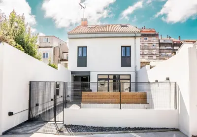 a house with white walls and a gate at Coliving Compostela in Santiago de Compostela