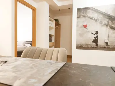 a room with a table and a painting of a girl with a balloon at milla sonsuites in Milladoiro