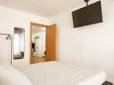 a white bedroom with a bed and a flat screen tv at milla sonsuites in Milladoiro
