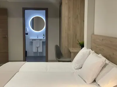 a bedroom with a bed and a bathroom with a sink at URBAN Pensión in Melide