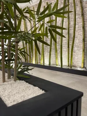 a plant in a black planter next to a brick wall at URBAN Pensión in Melide