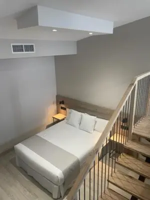 a bed in a room with a staircase at URBAN Pensión in Melide