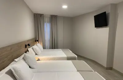 a hotel room with two beds and a flat screen tv at URBAN Pensión in Melide