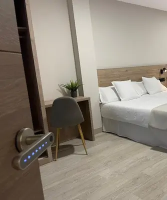 a bedroom with a bed and a chair and a door at URBAN Pensión in Melide