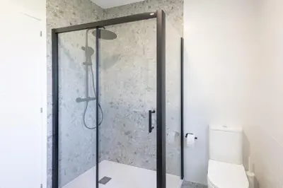 a glass shower door in a bathroom with a toilet at Miño Suites I in Miño