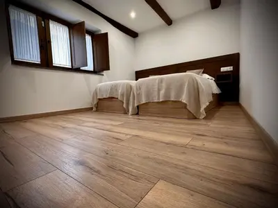 a bedroom with a bed and a wooden floor at La Casina de la Yeye San Cristóbal de Valdueza in San Cristóbal de Valdueza