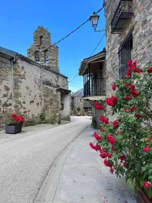 a street with red roses and a church at La Casina de la Yeye San Cristóbal de Valdueza in San Cristóbal de Valdueza