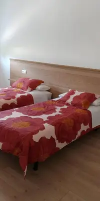 a bedroom with two beds with red and white blankets at Apartamentos Turísticos Magencio in Carucedo