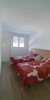 a bedroom with three beds with red and white sheets at Apartamentos Turísticos Magencio in Carucedo