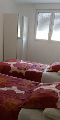 two beds sitting in a room with two windows at Apartamentos Turísticos Magencio in Carucedo
